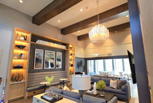 Modern residential interior featuring a stylish living room with gray sofas, decorative shelving, and a statement chandelier, showcasing Wilder Painting's quality finishes and design expertise.